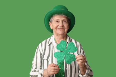 Yeşil arka planda yonca olan cüce şapkalı yaşlı kadın. Aziz Patrick Günü kutlaması