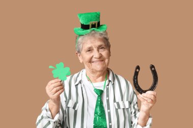 Kahverengi arka planda at nalı ve yonca olan cüce şapkalı yaşlı kadın. Aziz Patrick Günü kutlaması