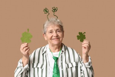 Kahverengi arka planda yonca olan saç bandı takan son sınıf öğrencisi bir kadın. Aziz Patrick Günü kutlaması