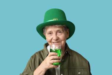 Leprikon şapkalı yaşlı kadın mavi arka planda bir bardak birayla. Aziz Patrick Günü kutlaması