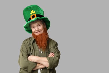 Gri arka planda kızıl sakallı cüce şapkalı yaşlı kadın. Aziz Patrick Günü kutlaması