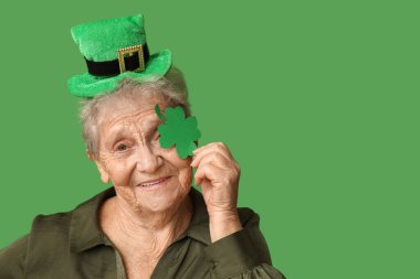 Yeşil arka planda yonca olan cüce şapkalı yaşlı kadın. Aziz Patrick Günü kutlaması