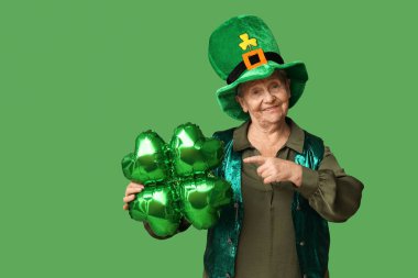 Yeşil arka planda yonca şeklinde balona bakan cüce şapkalı yaşlı kadın. Aziz Patrick Günü kutlaması