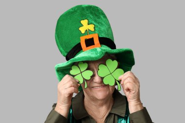 Leprikon şapkalı yaşlı kadın ve gri arka planda yonca. Aziz Patrick Günü kutlaması