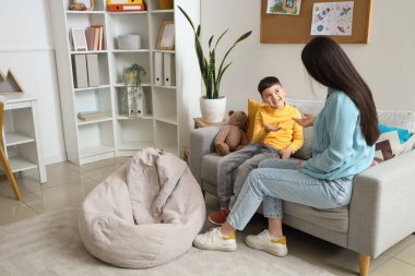 Ofisteki koltukta psikologla konuşan küçük çocuk.