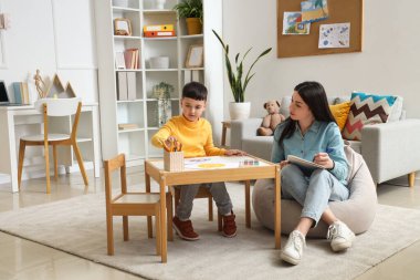 Kadın psikolog ve küçük çocuk ofiste resim çiziyorlar.