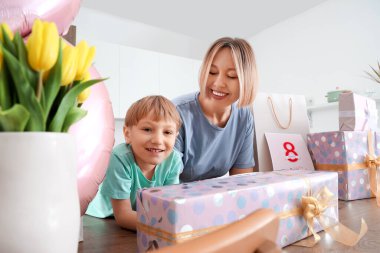 Küçük oğluyla mutlu bir anne ve mutfakta hediyeler. Uluslararası Kadınlar Günü