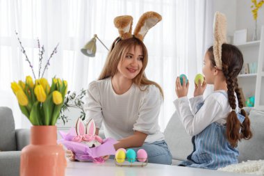 Paskalya yumurtaları ve evde tavşan kulaklı annesi olan sevimli küçük bir kız.