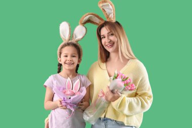 Paskalya pastalı şirin küçük kız ve yeşil arka planda tavşan kulaklı annesi.