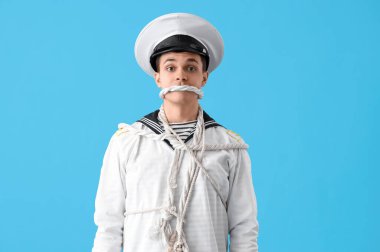 Genç denizci mavi arka planda iple bağlanmış.