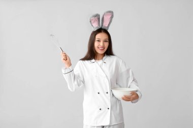 Tavşan kulaklı, çırpılmış çırpılmış ve arka planda kâse olan Asyalı kadın şef. Paskalya kutlaması