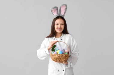 Paskalya yumurtaları hafif arka planda tavşan kulaklı Asyalı kadın şef.