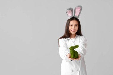 Tavşan kulaklı Asyalı kadın şef ve arka planda Paskalya tavşanı