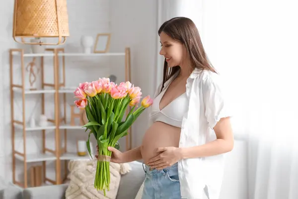 Young pregnant woman with tulips at home