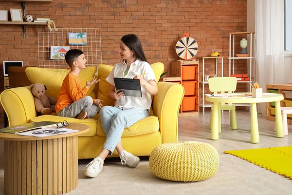 Ofisteki kanepede küçük çocukla çalışan kadın psikolog.