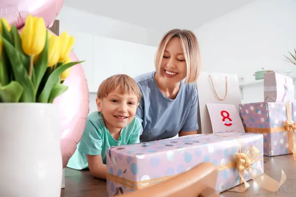 Küçük oğluyla mutlu bir anne ve mutfakta hediyeler. Uluslararası Kadınlar Günü