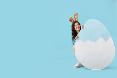 Büyük kağıt kulaklı, güzel bir kadın. Mavi arka planda Paskalya yumurtası.