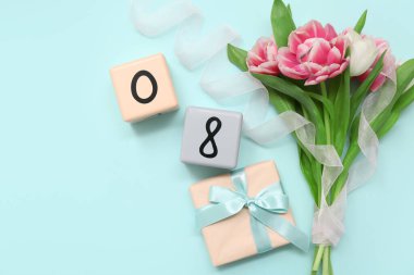 Küp takvimi, tarih 08, güzel laleler ve mavi arka planda hediye kutusu. Uluslararası Kadınlar Günü