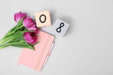 Küp takvimi, tarih 08, güzel mor laleler ve gri arka planda bir defter. Uluslararası Kadınlar Günü