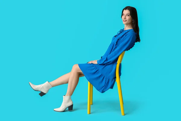 Schöne Junge Frau Stilvollem Blauen Kleid Auf Stuhl Vor Farbigem — Stockfoto