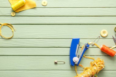 Yeşil ahşap arka planda farklı malzemelerle elle dikiş makinesi.