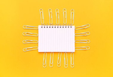 Turuncu arkaplanda not defteri ve ataç