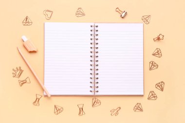 Turuncu arka planda farklı kırtasiye malzemesi içeren defter