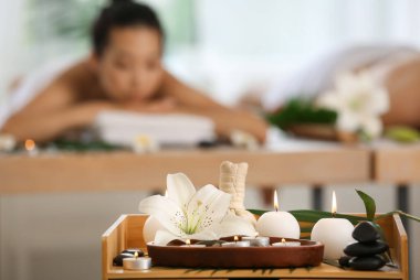 Salondaki masada yanan mumlar ve zambak çiçekli spa kompozisyonu, yakın plan.