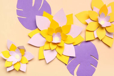 Renkli origami çiçekleri ve bej arkaplanda yapraklar