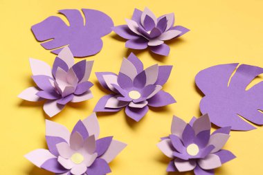 Renkli origami çiçekleri ve sarı arkaplanda yapraklar