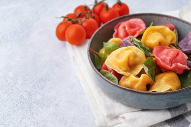 Beyaz arka planda ıspanaklı ve domatesli bir kase kaynamış renkli börek.