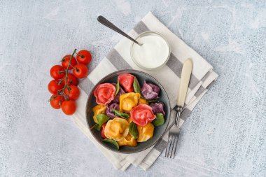 Beyaz arka planda ıspanaklı ve domatesli bir kase kaynamış renkli börek.