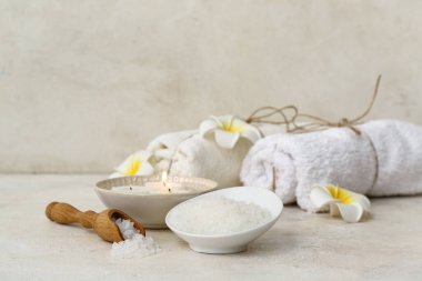 Bir kase deniz tuzu, yanan mumlar ve aydınlık masada temiz havlular.