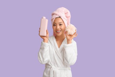 Bornozlu genç Asyalı kadın duş jeli ve lifli leylak arka planda