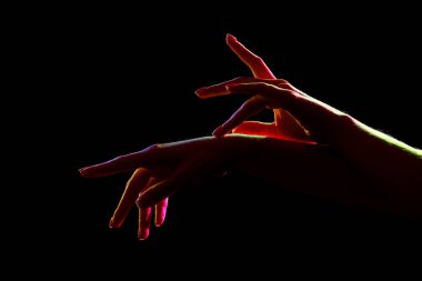 Koyu arkaplanda kadın eli silueti, yakın plan.