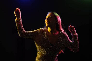 Karanlık arka planda dans eden genç bir kadının silueti.