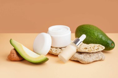 Renkli arka planda kozmetik ürünleri, taşlar ve avokado bileşimi