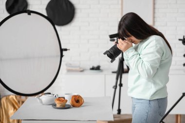 Stüdyoda kek fotoğrafı çeken kadın yemek fotoğrafçısı.