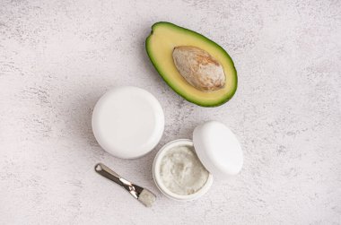 Hafif arka planda taze avokado ve kozmetik ürünleri kavanozları