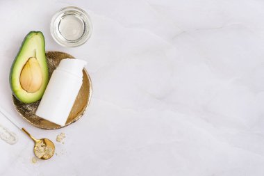 Hafif arka planda taze avokado, toz ve bir şişe kozmetik ürünü içeren kompozisyon