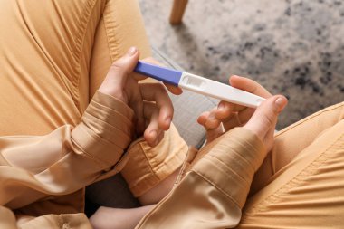 Evinde hamilelik testi olan bir kadın.