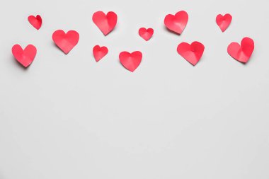 Gri zemin üzerinde kırmızı kağıt kalpler olan kompozisyon. Sevgililer Günü kutlaması