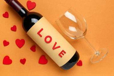 Turuncu arka planda Sevgililer Günü için şarap ve cam karışımı.