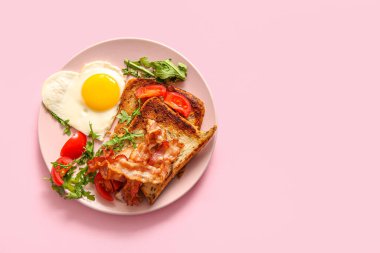 Lezzetli kızarmış yumurta, kızarmış ekmek, domates ve pembe arka planda roka.