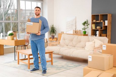 Evinde açık paket kutusu olan genç bir adam.