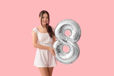 Pembe arka planda 8 şeklinde gümüş renkli hava balonu olan güzel bir Asyalı kadın. Uluslararası Kadınlar Günü