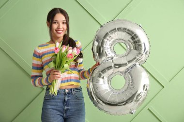 Şekil 8 şeklinde gümüş balonu ve yeşil arka planda bir buket güzel lalesi olan güzel Asyalı bir kadın. Uluslararası Kadınlar Günü