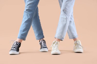 Bej arka planda farklı ayakkabılar giyen kadın bacakları.