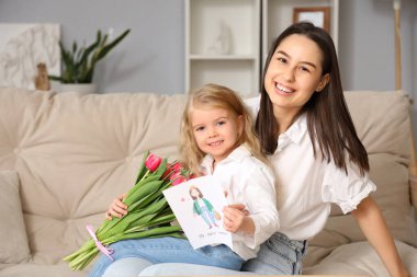 Küçük kız annesini bir buket çiçek ve tebrik kartıyla tebrik ediyor. Anneler Günü kutlaması