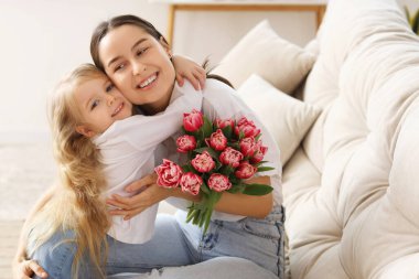 Küçük kız evde annesini bir buket çiçekle tebrik ediyor. Anneler Günü kutlaması
